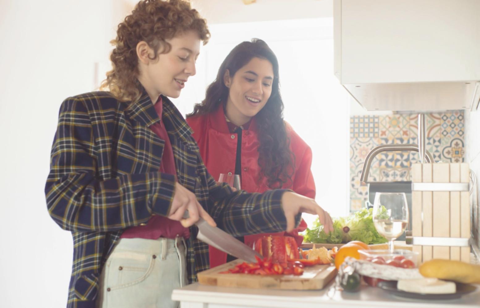 Students gathered around a kitchen island learning knife techniques for vegetable preparation